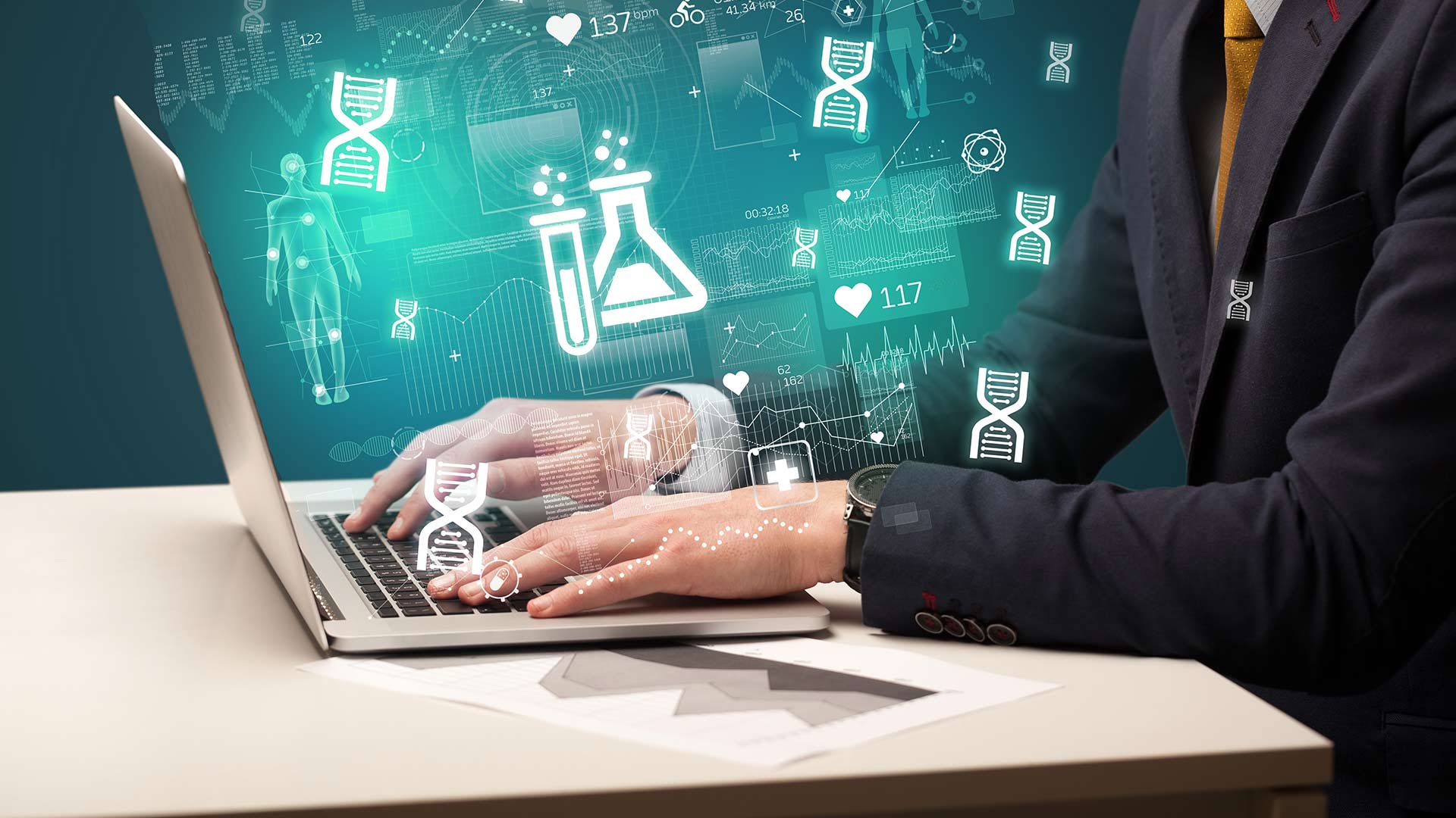 A person in a suit typing on a laptop, with glowing teal holographic overlays of medical and scientific icons like lab flasks, DNA strands, and heart rate data floating around the screen.